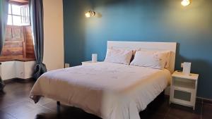 um quarto com uma cama branca e uma parede azul em Casa Tía Rosa. em Adeje