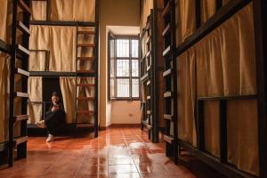 a woman sitting on a bench in a room with shelves at Flore Hostel in Antigua Guatemala