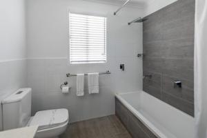 a white bathroom with a tub and a toilet at Ingenia Holidays Cairns Coconut in Cairns