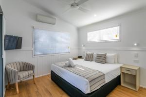 ein weißes Schlafzimmer mit einem Bett und einem Stuhl in der Unterkunft Ingenia Holidays Cairns Coconut in Cairns