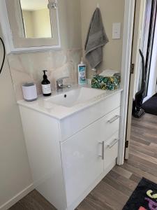 a bathroom with a white sink and a mirror at Peaceful Riverfront cottage in small northland town in Te Kopuru