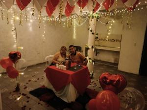 um homem e uma mulher sentados numa mesa numa sala com balões em VILLA BRAULIO em Rozo