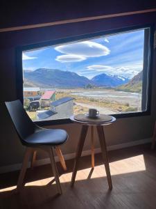 a table and a chair in front of a window at Desierto Suites in El Chalten