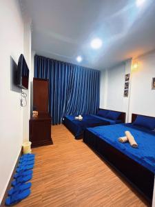 芹苴的住宿－Nhan Tay Hostel，一间卧室配有2张蓝色的床和电视