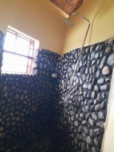 a bathroom with a shower with a rock wall at Lake Nyamirima cottages in Fort Portal