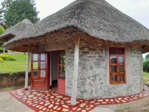 a small stone building with a thatched roof at Lake Nyamirima cottages in Fort Portal