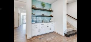 a kitchen with white cabinets and a staircase at Stylish townhome near AT&T Stadium, Globe Life, Six Flags & More in Arlington