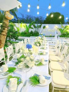 długi biały stół z białymi krzesłami i kwiatami w obiekcie Malis Homestay w mieście Trà Vinh