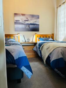 a bedroom with two beds and a desk at Modern Upstairs Apartment in Dunedin Central in Dunedin