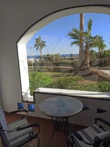 uma mesa e cadeiras num quarto com uma janela em Bellissimo appartamento vista mare sulla piscina em Sharm el Sheikh