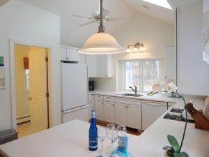 a kitchen with a white refrigerator and a table with wine glasses at 142 George Ryder Road South Chatham Cape Cod - - Sweet Serenity in Chatham