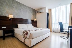 a hotel room with a bed and a desk and a bed sidx sidx at De' Garden Hotel, Butterworth in Butterworth