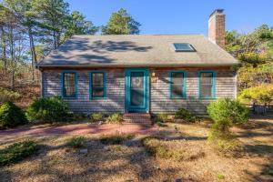 a small house with a blue door in a yard at Turtle Dreams: Cozy Cape Cod Bayside Retreat in Eastham