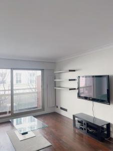 a living room with a table and a tv on the wall at Belle chambre Champs-Élysée in Paris +17 photos