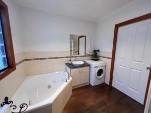 a bathroom with a tub and a washing machine at The Kingfisher Lodge 111 in Halls Gap +16 photos