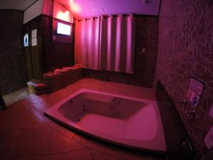 bañera rosa en el baño con iluminación rosa en Motel Scorpios, en Lages