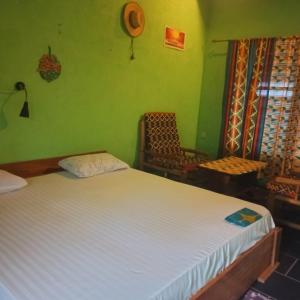 a bedroom with a white bed and a chair at Scorpion Hill Lodge in Busua