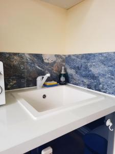 ein weißes Waschbecken im Bad mit blauen Fliesen in der Unterkunft Martinique La Trinité KAZAKASSY Studio plain-pied, fonctionnel et vue mer in La Trinité