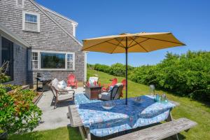 a patio with a table with an umbrella and chairs at 229 Scatteree Road North Chatham Cape Cod - - Nauset Watch in South Chatham