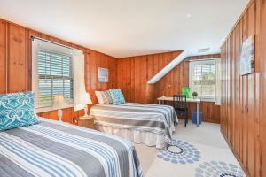 two beds in a room with wooden walls and windows at 229 Scatteree Road North Chatham Cape Cod - - Nauset Watch in South Chatham