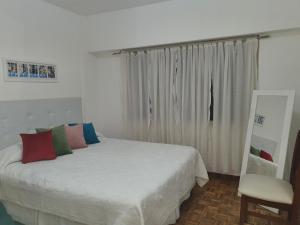 ein Schlafzimmer mit einem weißen Bett und einem Stuhl in der Unterkunft Monoambiente Centro ESTRATÉGICA UBICACIÓN in Buenos Aires