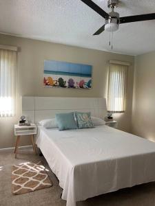 um quarto com uma cama branca e uma ventoinha de tecto em Sunshine Paradise em Cape Coral