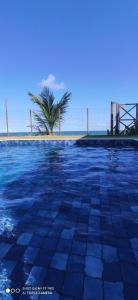 a swimming pool with a palm tree in the background at Pé na areia Itacimirim in Camacari