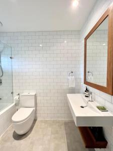 bagno con servizi igienici, lavandino e specchio di The Beach Shack Byron Bay a Byron Bay