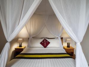 a bedroom with a white bed with a canopy at Avery Le Nixsun Villas Uluwatu by Waringin Hospitality in Jimbaran