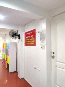 Zimmer mit einem Kühlschrank und einem Schild an der Wand in der Unterkunft Dormitels.ph The Fort BGC in Manila