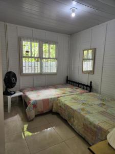 - une chambre avec un grand lit et 2 fenêtres dans l'établissement Casa Praia da Lagoinha, à Florianópolis