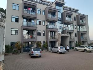 a large building with cars parked in a parking lot at Ella Apartment Albert Cook Road in Kampala