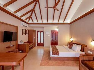 a hotel room with a bed and a flat screen tv at Abad Turtle Beach in Mararikulam