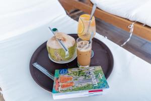 a tray with a drink and a sandwich and a book at ARECA HOTEL NHA TRANG in Nha Trang