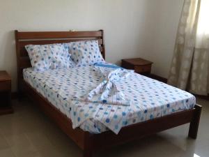 a bed with blue and white sheets and pillows at E Gravana in São Tomé