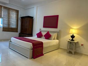 a bedroom with a bed with pink pillows and a lamp at City Stay By Sunrise in Colombo