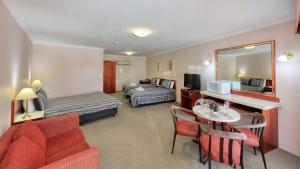 um quarto de hotel com uma cama e uma sala de estar em Southern Comfort Motor Inn em Cootamundra
