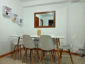 a dining room table with white chairs and a mirror at Elegante y acogedor departamento entero # 3 in Víctor Larco Herrera