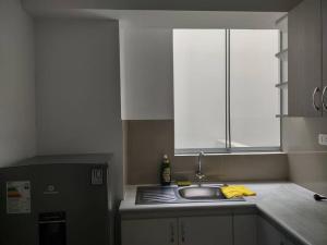 Elle comprend une petite cuisine avec un évier et une fenêtre. dans l'établissement Elegante y acogedor departamento entero # 3, à Víctor Larco Herrera
