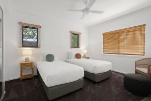 two beds in a room with white walls and windows at 1 Horizon Terraces Beautifully Styled Duplex Perfect Beach Vibes in Sunshine Beach +26 photos