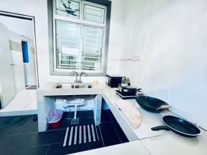 ein Badezimmer mit einem Waschbecken, einem Fenster und einem Waschbecken in der Unterkunft SingBeach holiday house in Mersing