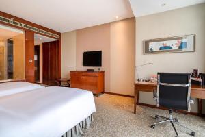 a hotel room with a bed and a desk and a television at Crowne Plaza Zhenjiang, an IHG Hotel in Zhenjiang