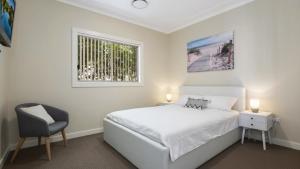 a bedroom with a bed and a chair and a window at Mara Bello - Umina Beach in Umina