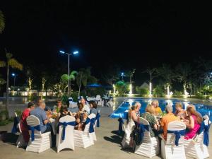 a group of people sitting in chairs in front of a pool at Sangkahak Mith Hotel in Kep