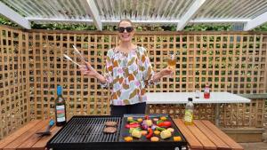 Eine Frau, die vor einem Grill mit einer Flasche Wein steht. in der Unterkunft Southern Comfort Motor Inn in Cootamundra