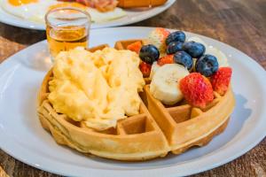 a waffle with fruit on a plate on a table at Jasaen Stylish Boutique Hotel in Bangkok