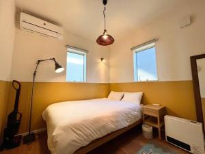een slaapkamer met een wit bed en 2 ramen bij studio Symphonia x Fukutsu 