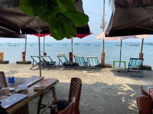 um grupo de cadeiras, mesas e guarda-sóis na praia em Bai Huong homestay em Hoi An