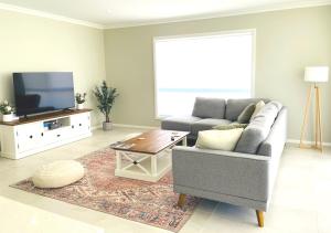 een woonkamer met een bank en een tv bij Coolalta Cottage - Hunter Valley in Nulkaba