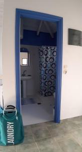 a bathroom with a blue doorway with a green bag at Il Veliero in Fiskardo